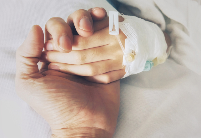 holding childs hand with IV